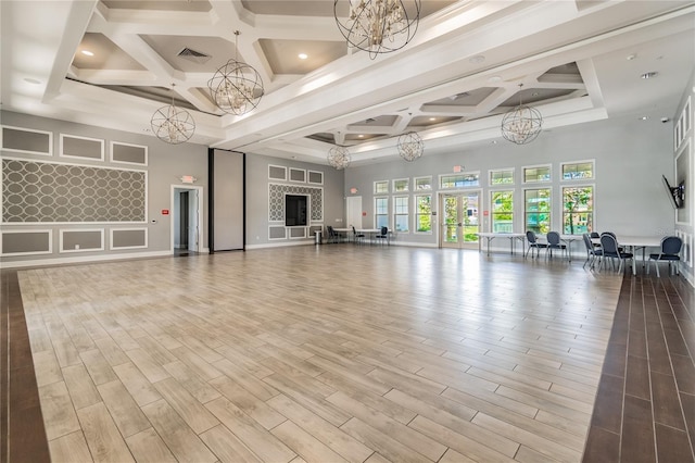 exercise area featuring a high ceiling, a notable chandelier, and coffered ceiling