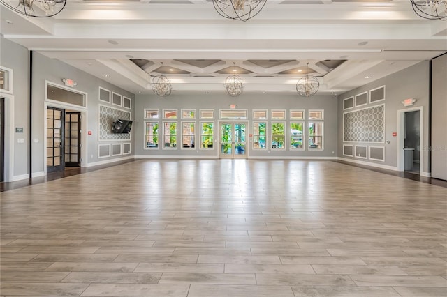 workout area with coffered ceiling, a chandelier, and a healthy amount of sunlight