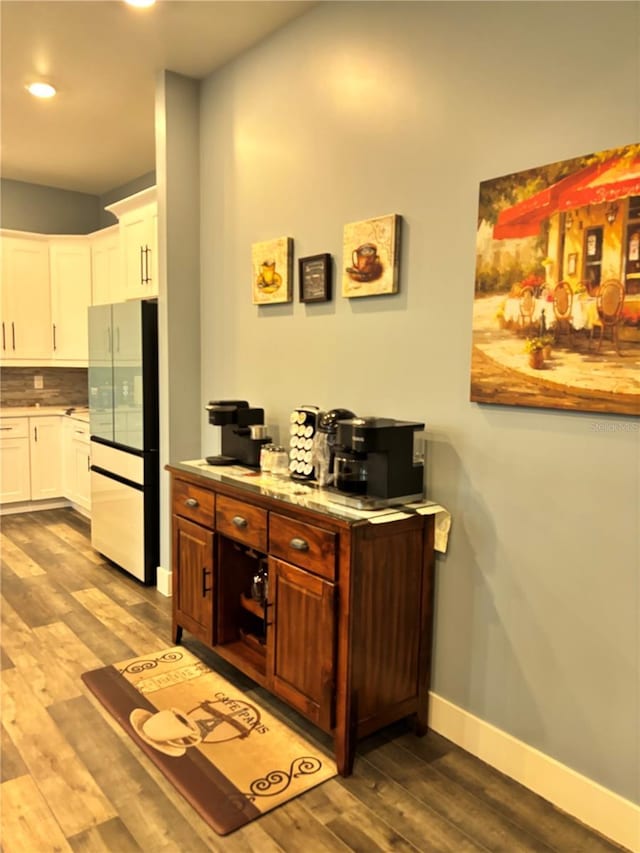 interior space featuring light hardwood / wood-style floors, decorative backsplash, white fridge, and white cabinetry