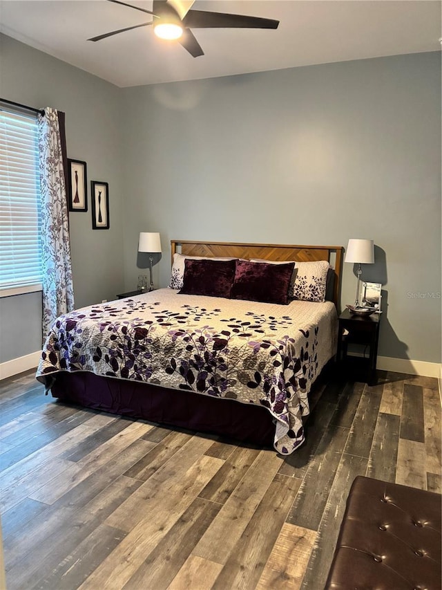 bedroom featuring ceiling fan, dark wood-type flooring, and multiple windows