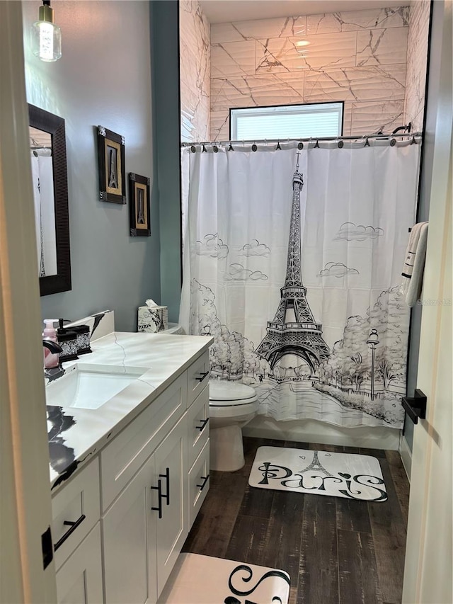 bathroom with toilet, hardwood / wood-style flooring, vanity, and curtained shower