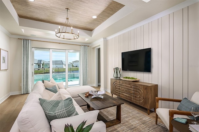 living room featuring recessed lighting, a raised ceiling, an inviting chandelier, light wood-type flooring, and baseboards