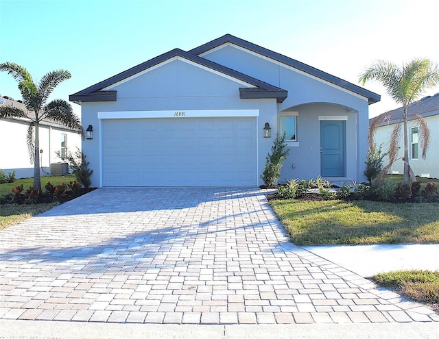 ranch-style home with a garage, decorative driveway, a front yard, and stucco siding