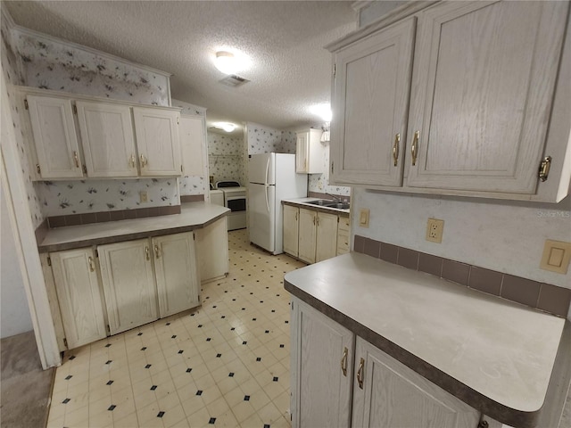 kitchen with white fridge, sink, a textured ceiling, and washer / clothes dryer