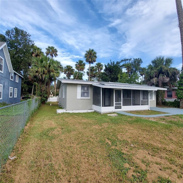 rear view of house with a sunroom and a lawn