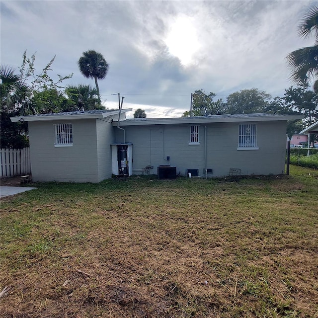 rear view of house featuring a lawn and central AC