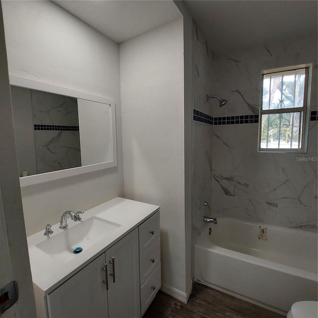 full bathroom with hardwood / wood-style flooring, toilet, vanity, and tiled shower / bath