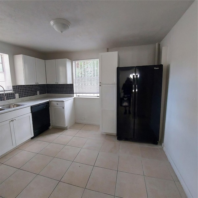 kitchen with white cabinetry, sink, tasteful backsplash, light tile patterned floors, and black appliances