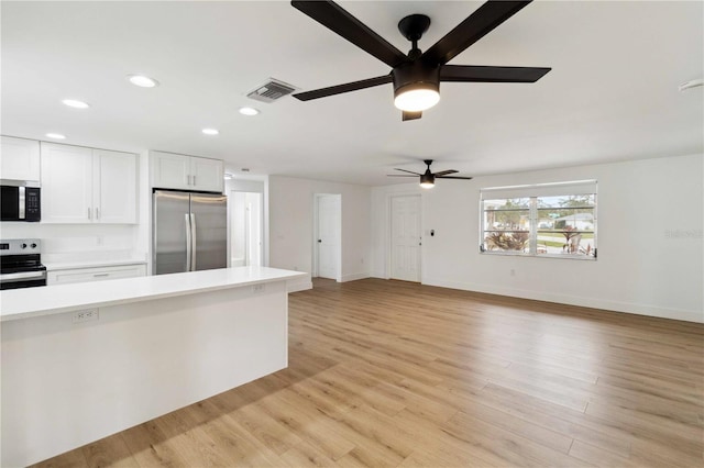 kitchen with ceiling fan, stainless steel appliances, light wood-type flooring, and white cabinets