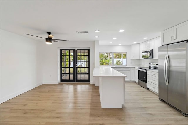 kitchen with a center island, french doors, white cabinets, and appliances with stainless steel finishes