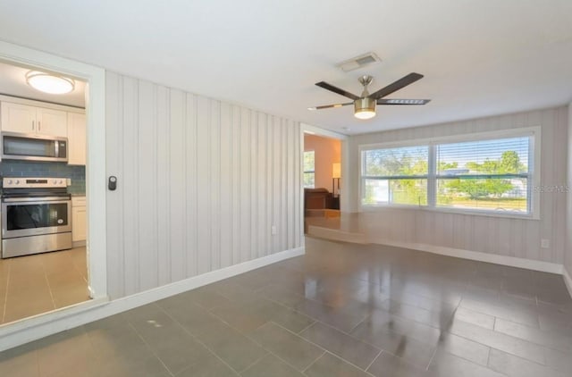 tiled spare room featuring ceiling fan