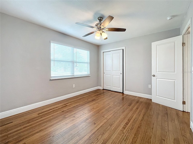 unfurnished bedroom featuring ceiling fan, a closet, and hardwood / wood-style flooring