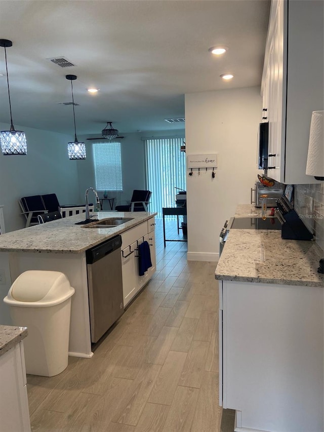 kitchen featuring appliances with stainless steel finishes, sink, white cabinets, hanging light fixtures, and a center island with sink