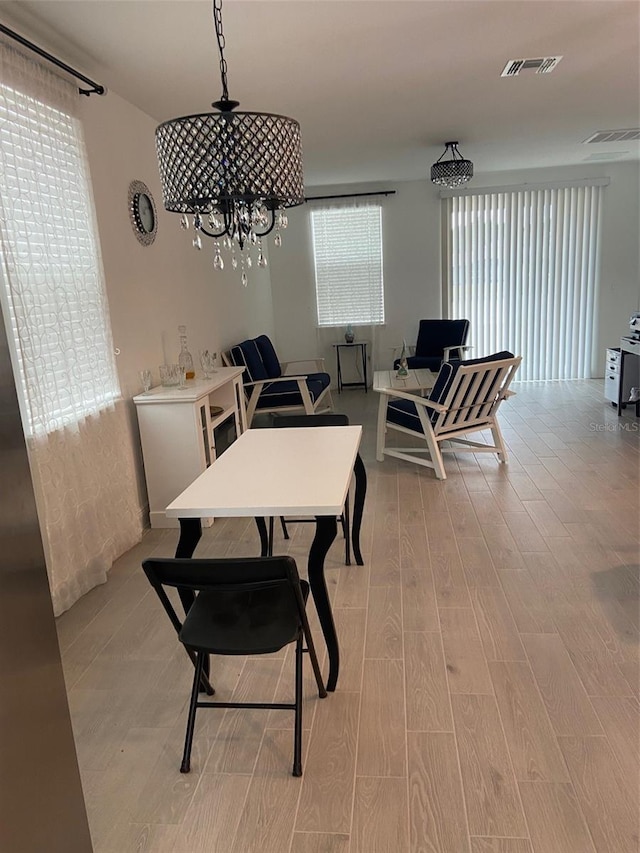 dining space with a notable chandelier, plenty of natural light, and light wood-type flooring