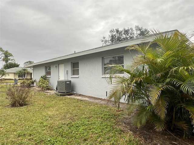 back of property with central AC and a lawn