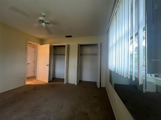 unfurnished bedroom featuring carpet flooring and two closets