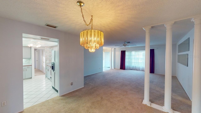 empty room featuring light carpet, ceiling fan with notable chandelier, decorative columns, and a textured ceiling