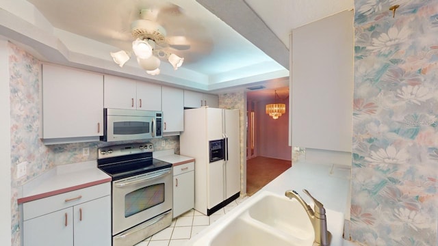 kitchen featuring a raised ceiling, sink, white cabinets, backsplash, and stainless steel appliances