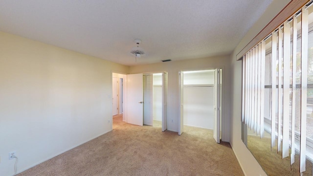 unfurnished bedroom with light carpet and two closets