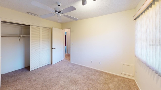 unfurnished bedroom featuring ceiling fan, light colored carpet, a closet, and a textured ceiling