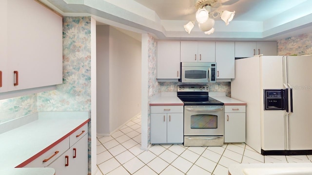 kitchen featuring white cabinetry, appliances with stainless steel finishes, a tray ceiling, and light tile patterned flooring