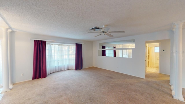 carpeted spare room with ceiling fan, a textured ceiling, and ornate columns