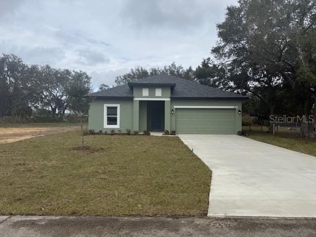 view of front of house featuring an attached garage, concrete driveway, a front yard, and stucco siding