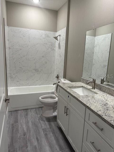 bathroom with a textured ceiling, toilet, wood finished floors, vanity, and tub / shower combination