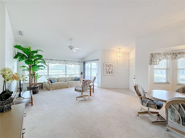 living room with vaulted ceiling, light colored carpet, ceiling fan, and a textured ceiling