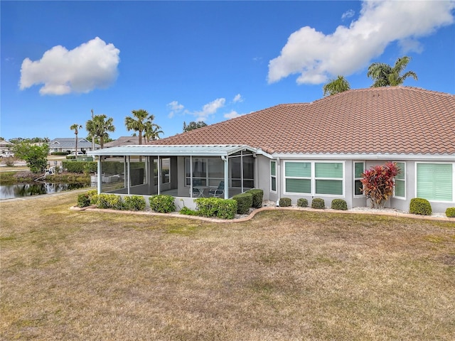 back of property with a water view, a yard, and a sunroom