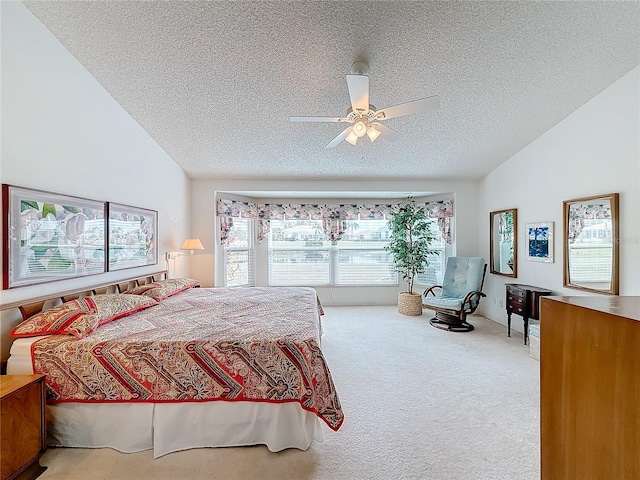 bedroom with lofted ceiling, ceiling fan, carpet floors, and a textured ceiling