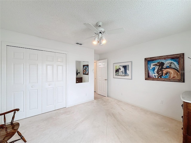 carpeted bedroom with ceiling fan, a closet, and a textured ceiling