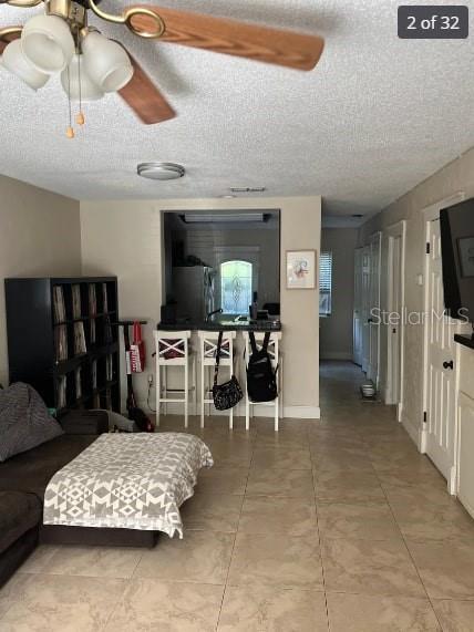 living room featuring ceiling fan and a textured ceiling