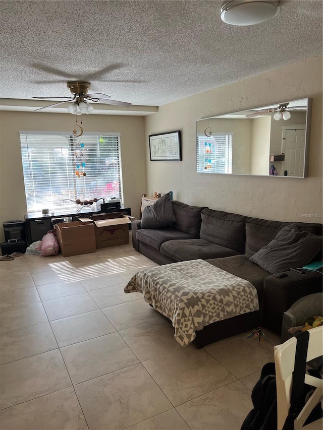 living room featuring ceiling fan, a textured ceiling, and light tile patterned floors