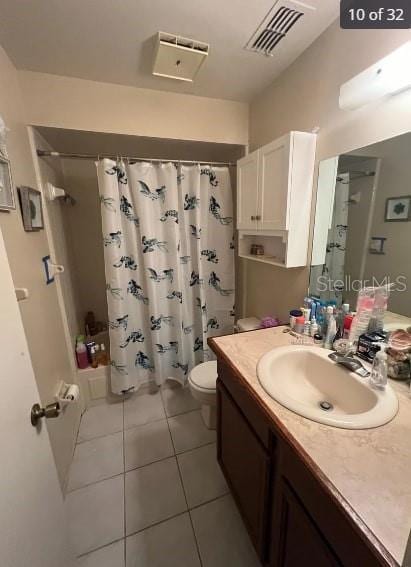 full bathroom featuring tile patterned flooring, vanity, shower / bath combo with shower curtain, and toilet