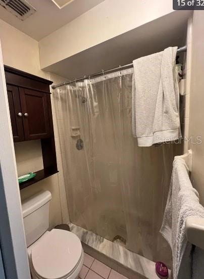 bathroom featuring a shower with curtain, toilet, and tile patterned flooring