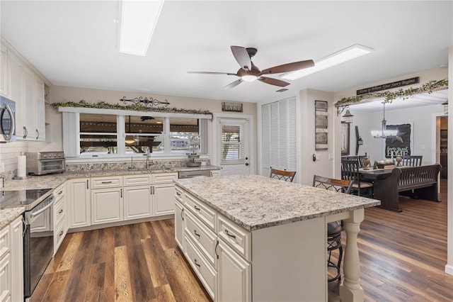 kitchen featuring a breakfast bar, appliances with stainless steel finishes, white cabinetry, dark hardwood / wood-style floors, and a kitchen island