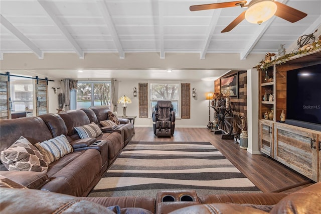 living room featuring beamed ceiling, a barn door, dark wood-type flooring, and a wealth of natural light