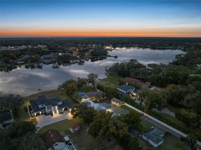 aerial view at dusk featuring a water view