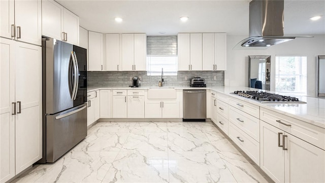 kitchen featuring sink, appliances with stainless steel finishes, white cabinetry, tasteful backsplash, and island exhaust hood