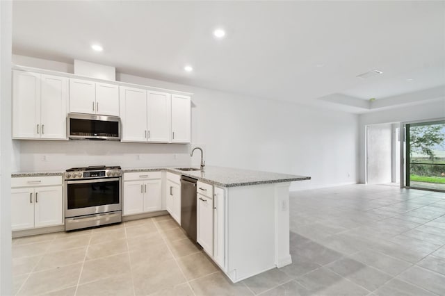 kitchen featuring stainless steel appliances, sink, white cabinets, and light stone counters