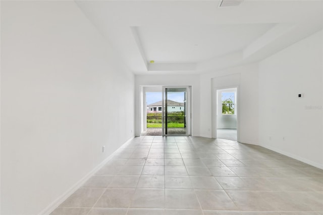 unfurnished room with light tile patterned floors and a tray ceiling