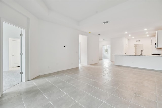 unfurnished living room featuring sink and light tile patterned floors