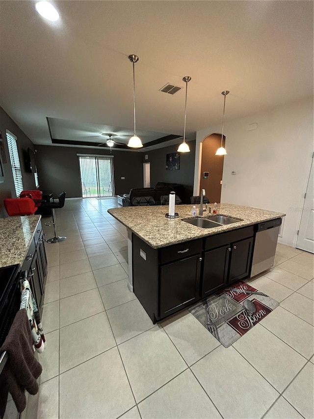 kitchen with sink, dishwasher, pendant lighting, light stone countertops, and a kitchen island with sink