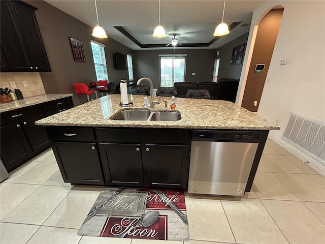 kitchen featuring tasteful backsplash, dishwasher, an island with sink, sink, and a tray ceiling