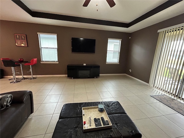 tiled living room featuring ceiling fan and a tray ceiling