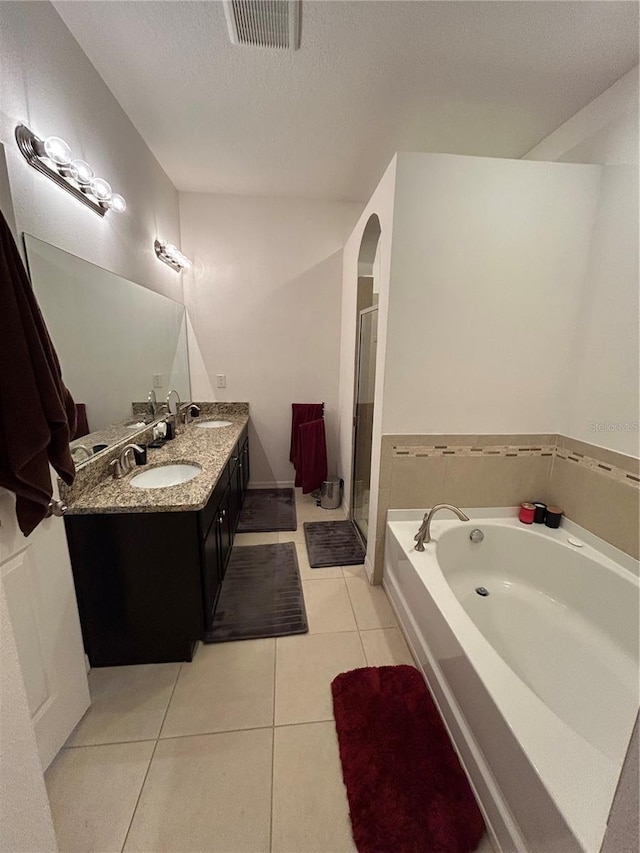 bathroom with tile patterned flooring, vanity, independent shower and bath, and a textured ceiling