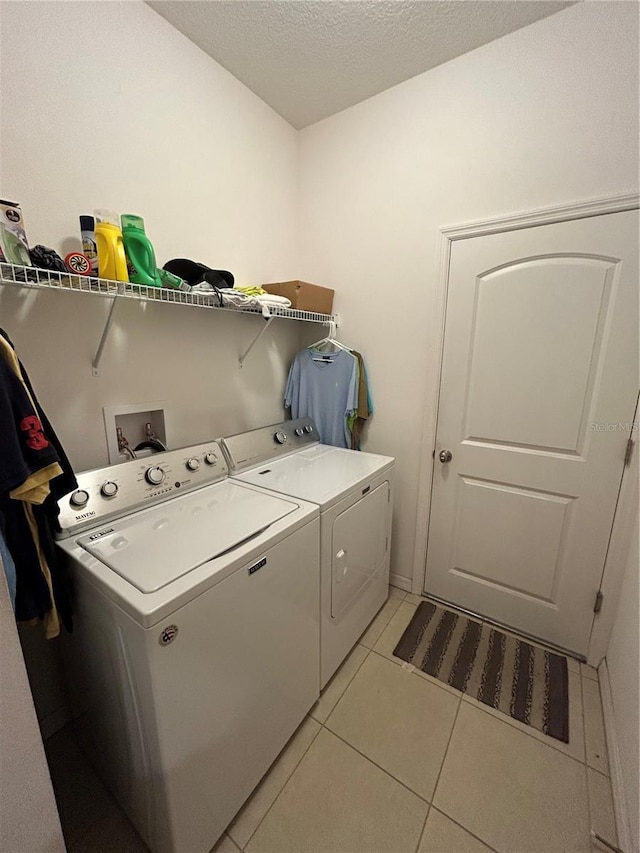 clothes washing area with separate washer and dryer, light tile patterned floors, and a textured ceiling