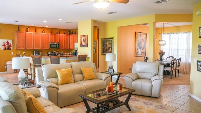 tiled living room featuring ceiling fan with notable chandelier