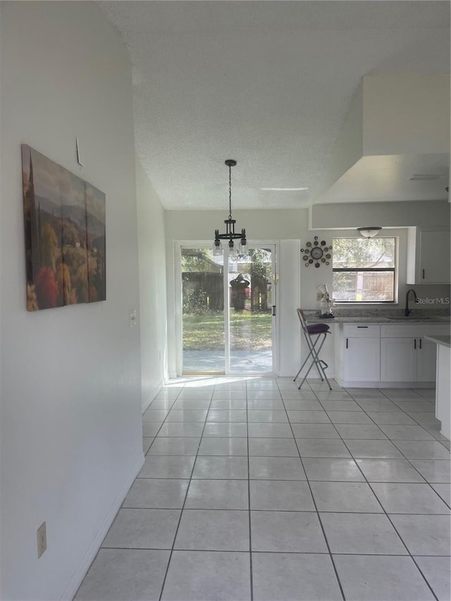 unfurnished dining area with light tile patterned flooring, sink, a notable chandelier, and a textured ceiling